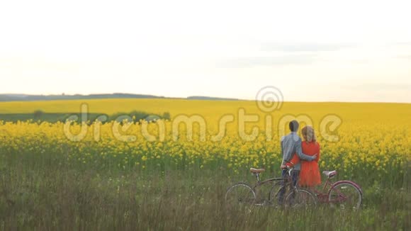 可爱的情侣们骑着自行车轻轻地拥抱着享受着这片美丽的田野视频的预览图