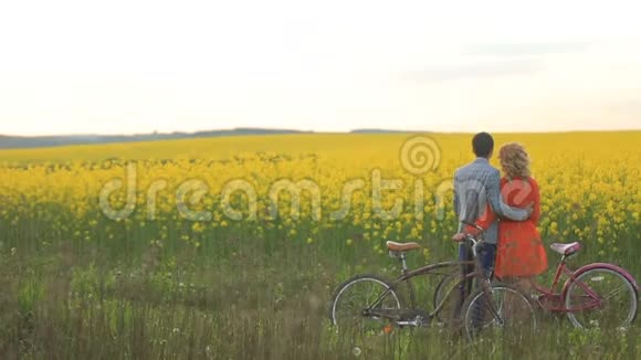 情侣们骑着自行车拥抱着享受着田野的喧闹视频的预览图