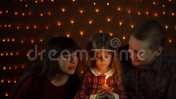 一个小女孩和爸爸妈妈一起在节日蛋糕上吹蜡烛视频的预览图