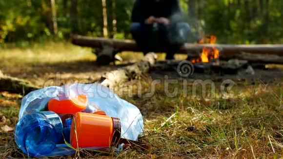 一个人在大自然中扔一个塑料瓶在背景户外娱乐自然和垃圾中燃烧视频的预览图