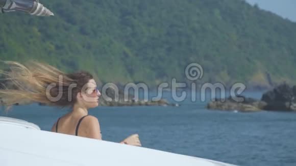 一个戴太阳镜的漂亮女孩正在游艇上航行看着大海视频的预览图