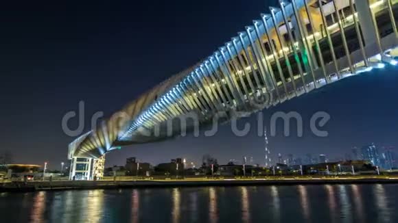 迪拜水上运河上空的未来派行人天桥在夜间延时超垂照明阿联酋视频的预览图