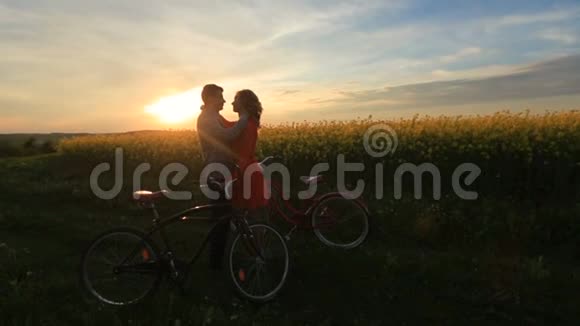 在盛开的田野里带着自行车的敏感相爱的夫妇新郎正在温柔地抚摸他爱人的脸视频的预览图