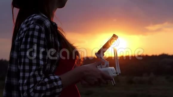 年轻女子在日落时操纵一架无人机视频的预览图
