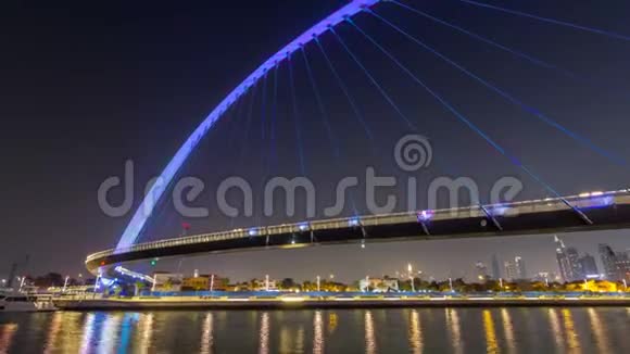 迪拜水上运河上空的未来派行人天桥在夜间延时超垂照明阿联酋视频的预览图