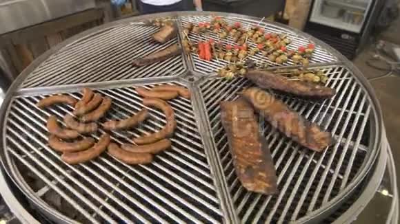 一个大的圆形烤架被分成几个部分围绕着它的轴线烤品种和肉类和蔬菜在上面视频的预览图