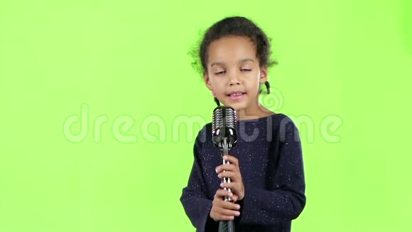 一个穿着复古麦克风唱歌的非裔美国女孩的孩子绿色屏幕慢动作视频的预览图