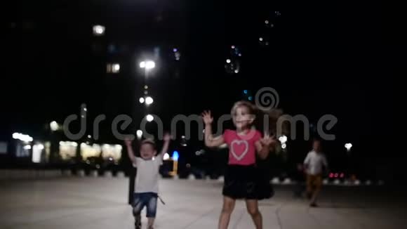 快乐的一群孩子在公园里玩肥皂泡孩子们晚上在公园里捕捉肥皂泡视频的预览图