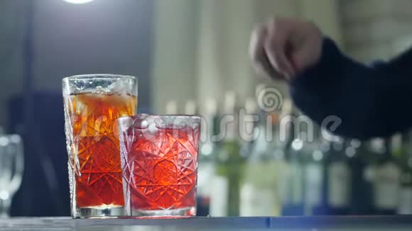 男人用手将红色浆果撒入清爽的鸡尾酒中在没有聚焦的背景上加入冰块视频的预览图