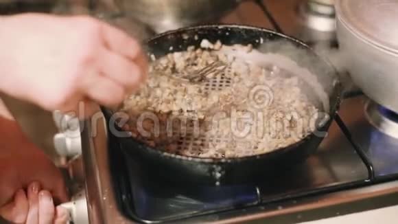 女人在铸铁厨房的煎锅上用洋葱炒蘑菇视频的预览图