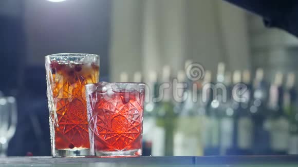 人的手臂将蔓越莓洒到冷却饮料中在玻璃特写镜头中加入冰块视频的预览图