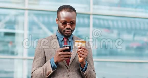 美国黑人青年戴墨镜在城市用智能手机上网购物视频的预览图