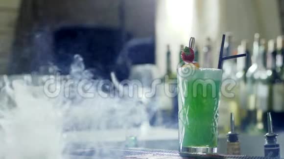 美丽的鸡尾酒黑吸管和草莓在玻璃看台上的酒吧桌子雾视频的预览图