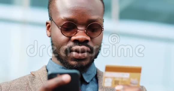 美国黑人青年戴墨镜在城市用智能手机上网购物视频的预览图