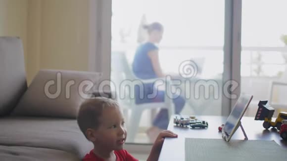孩子在平板电脑上看动画片而工作的妈妈视频的预览图