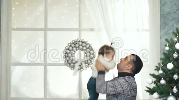 快乐的爸爸在圣诞树前抚养他的小孩玩耍视频的预览图