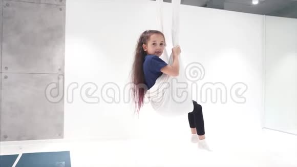 一位美丽的年轻女孩在画布上从事飞行瑜伽的肖像视频的预览图