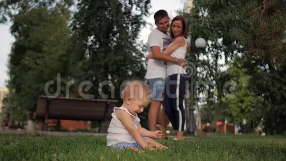 幸福家庭的肖像小男孩坐在公园里父母看着他概念家庭放松视频的预览图