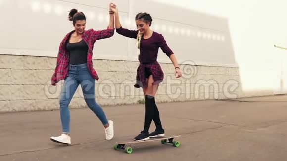 嘲笑年轻的时髦女孩被一个朋友教滑板他支持她牵着她的手慢动作视频的预览图