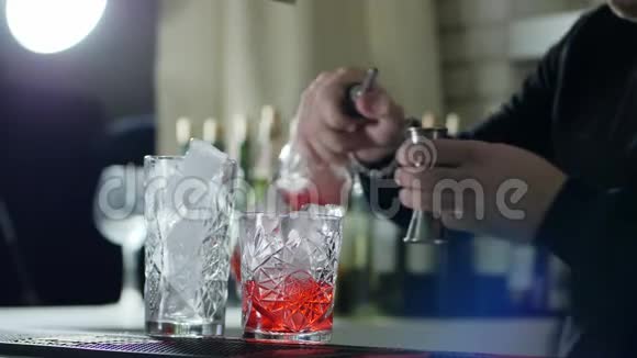 将瓶子放入手臂中的人测量酒在跳汰机中的比例并将其倒入带有冰块的玻璃中视频的预览图