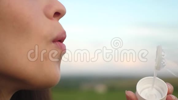 年轻女孩在蓝天上吹着透明的肥皂泡笑慢动作视频的预览图
