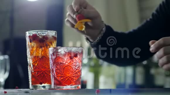 男人的双手用浆果和橙皮装饰在桌子上的大玻璃杯里在淡淡的雾中提神饮料视频的预览图