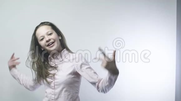 一个穿着白色衬衫的酷少年女孩一个美丽的女孩在白色背景上的缓慢动作视频的预览图