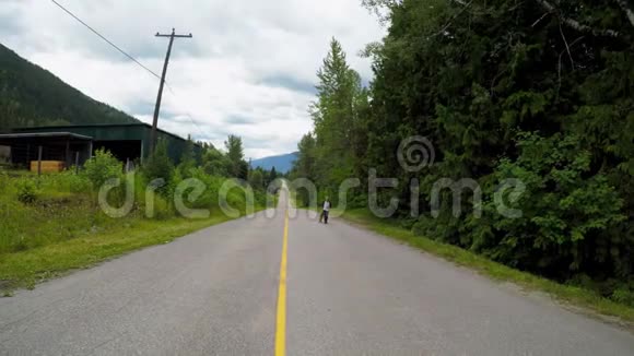 男子带着滑板在乡村道路上行走视频的预览图