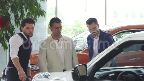 三个男性朋友在经销商处检查汽车出售视频的预览图