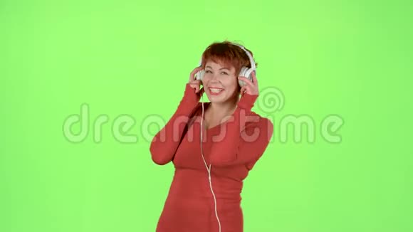 红头发的女人在耳机上听音乐绿色屏幕视频的预览图