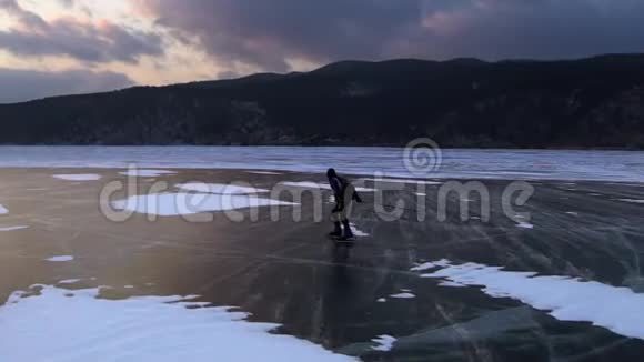 在美丽的日落中人们在冰冻的贝加尔湖的冰上滑冰视频的预览图