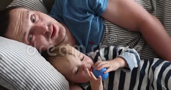父亲和孩子早上躺在床上特写视频的预览图