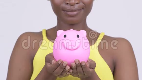 快乐的非洲年轻女子微笑着拿着储蓄罐视频的预览图
