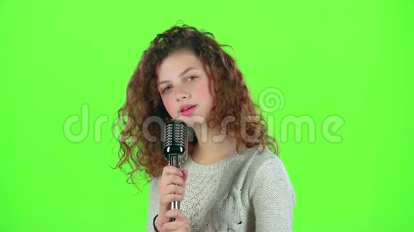 少女用复古麦克风唱火辣辣的歌绿色屏幕视频的预览图