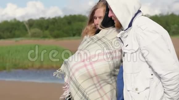 一位孕妇在湖边拥抱她的丈夫年轻的家庭期待着孩子走进来视频的预览图