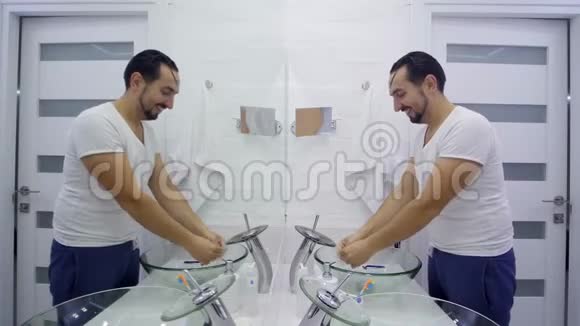 人在镜子前洗澡穿白色T恤的没胡子的家伙视频的预览图