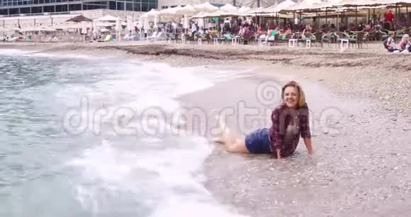 海滩上漂亮的金发女孩为摄影师摆姿势视频的预览图