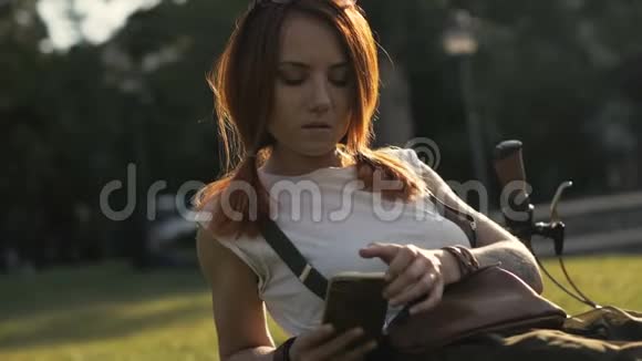 夏日公园骑自行车的妇女在手机上打字视频的预览图