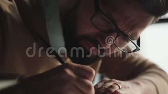 专心致志的人留着胡子戴着画的眼镜做笔记视频的预览图