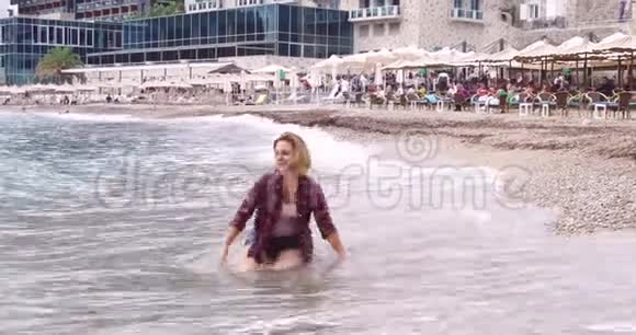 海滩上漂亮的金发女孩为摄影师摆姿势视频的预览图