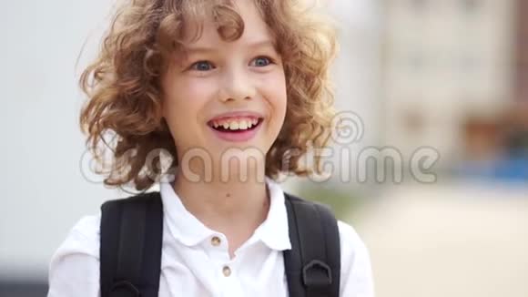甜蜜而快乐的卷曲蓝眼睛男孩笑着看着相机男生穿着一件白色衬衫视频的预览图