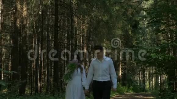 美丽的年轻夫妇穿着白色衣服在树林里散步视频的预览图