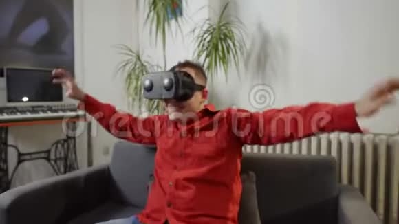 身穿红衫的男士在家里穿上虚拟现实享受视频的预览图