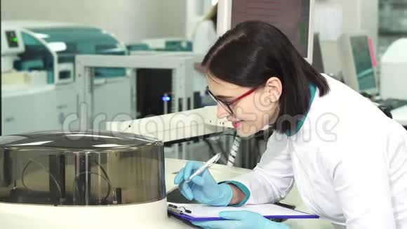 年轻的女化学家在现代实验室做笔记视频的预览图