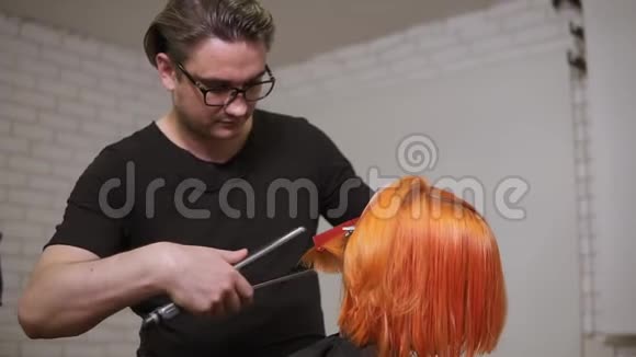 男性专业的理发师正在理发店里用亮红色女人的发型视频的预览图