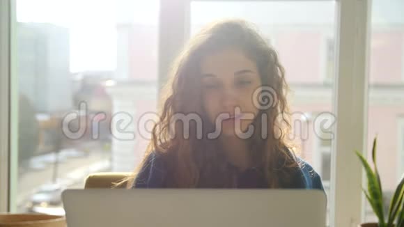 年轻女子在窗口前浏览电脑视频的预览图