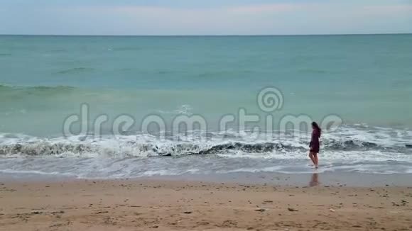 海滩上散步的美丽年轻女子的夏日景色视频的预览图