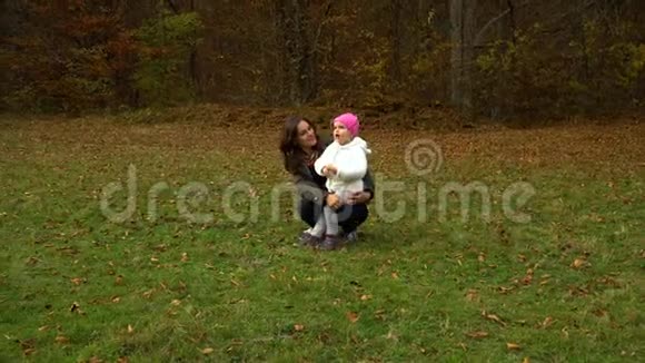 一位年轻的母亲和她的小女儿在秋天的森林里玩耍妈妈和女儿交流他们很开心视频的预览图