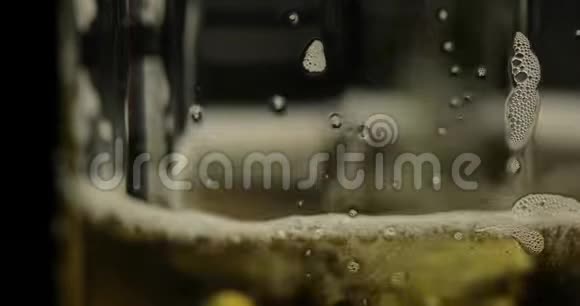 将冰冷的金光啤酒倒入玻璃杯中手工啤酒制造气泡和泡沫视频的预览图