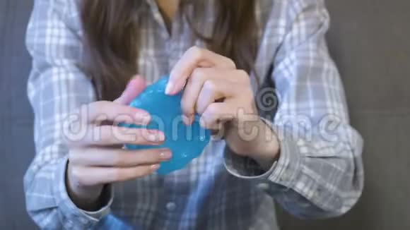 女人正在伸展一个蓝色的黏液和玩耍特写双手视频的预览图